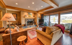 The cozy living room space with a fireplace and large windows in Comet Cove vacation rental in Lake Placid, NY
