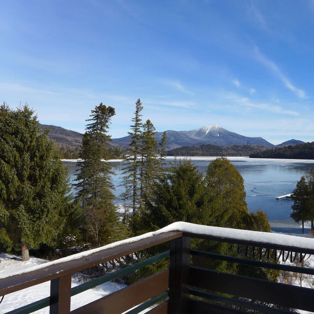 Daytime view of Lake Placid lake in winter with Whiteface Mountain in the background from the porch of a Merrill L. Thomas waterfront vacation rental